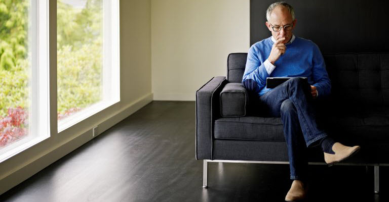 Contemplative man looking at a tablet computer, suggesting checking the return on his investment