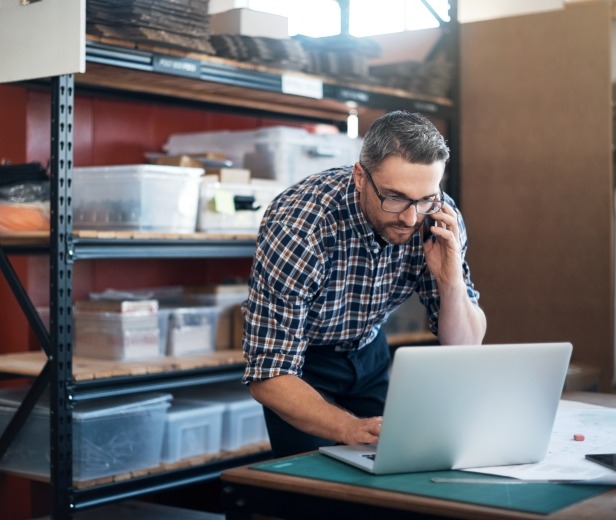 A man working on a laptop amid supplies, suggesting small-business ownership
